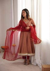 Woman in traditional outfit with red dupatta against a white curtain background